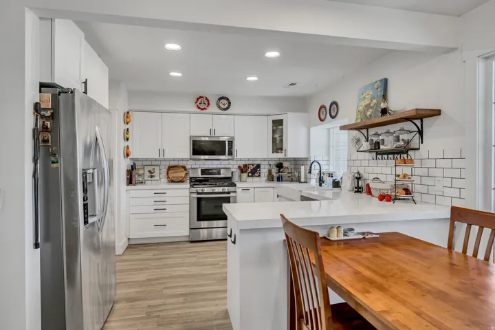 Modern kitchen featuring white shaker cabinetry, stainless steel appliances, white subway tile backsplash, and wood-finish flooring