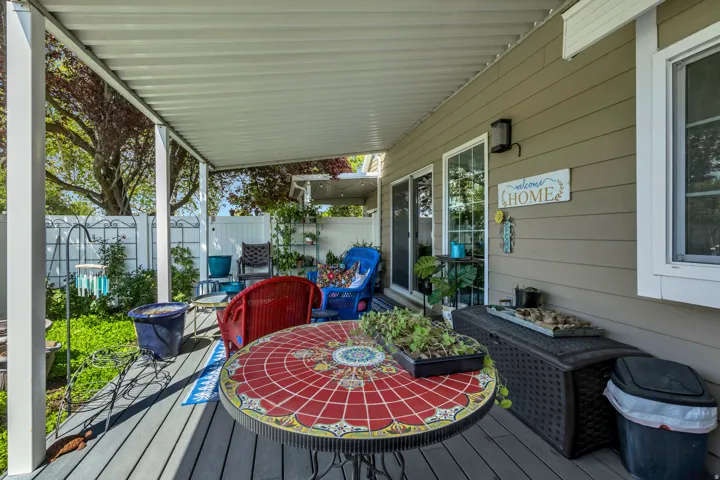 Covered patio featuring plank decking, white aluminum posts, and an overhead awning