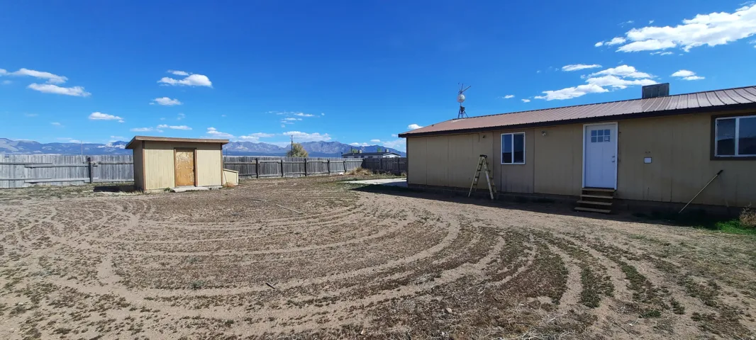 Expansive property featuring a detached shed, full perimeter fencing, and a large dwelling with a metal roof