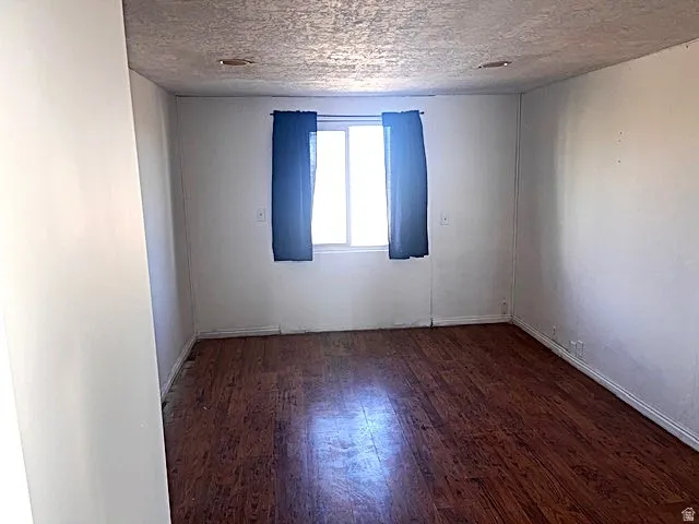 Room with wood-finish flooring, white walls, and a window providing natural illumination