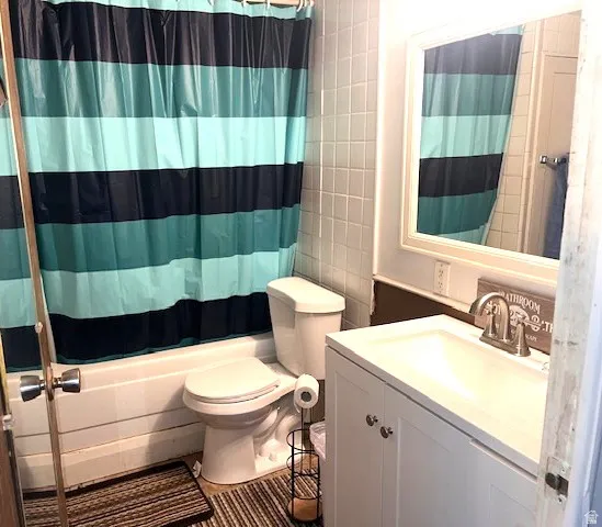 Bathroom featuring a white vanity with a single sink, an integrated mirror with a white frame, and white wall tiling