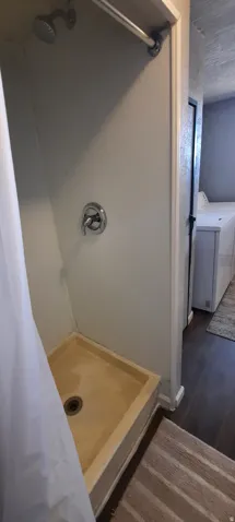 Shower stall with chrome fixtures and a stone-finish shower pan