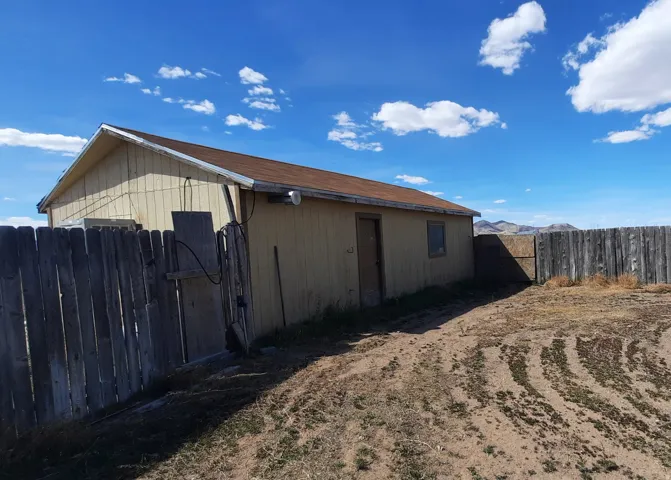 Property exterior featuring horizontal siding, a gabled roof with shingles, a wooden privacy fence, and a distant mountain range