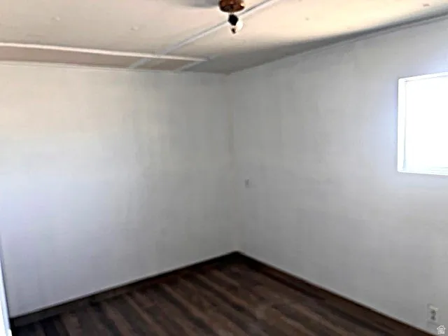 Interior space featuring wood-finish flooring, white walls, and a single window for natural light