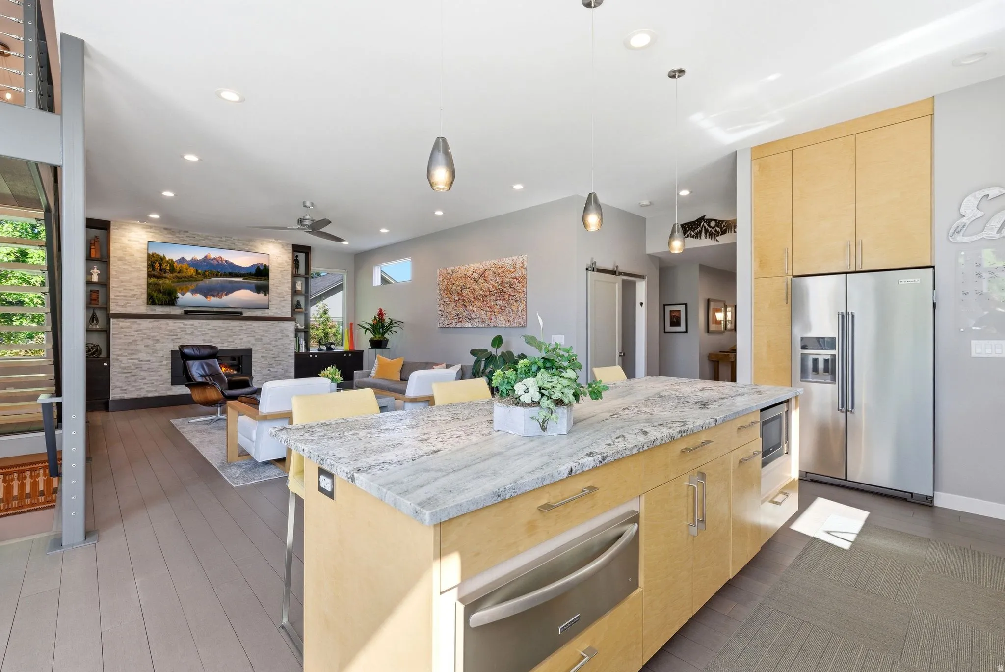 Kitchen island with a light-toned granite countertop featuring integrated appliances and light wood-finish cabinetry