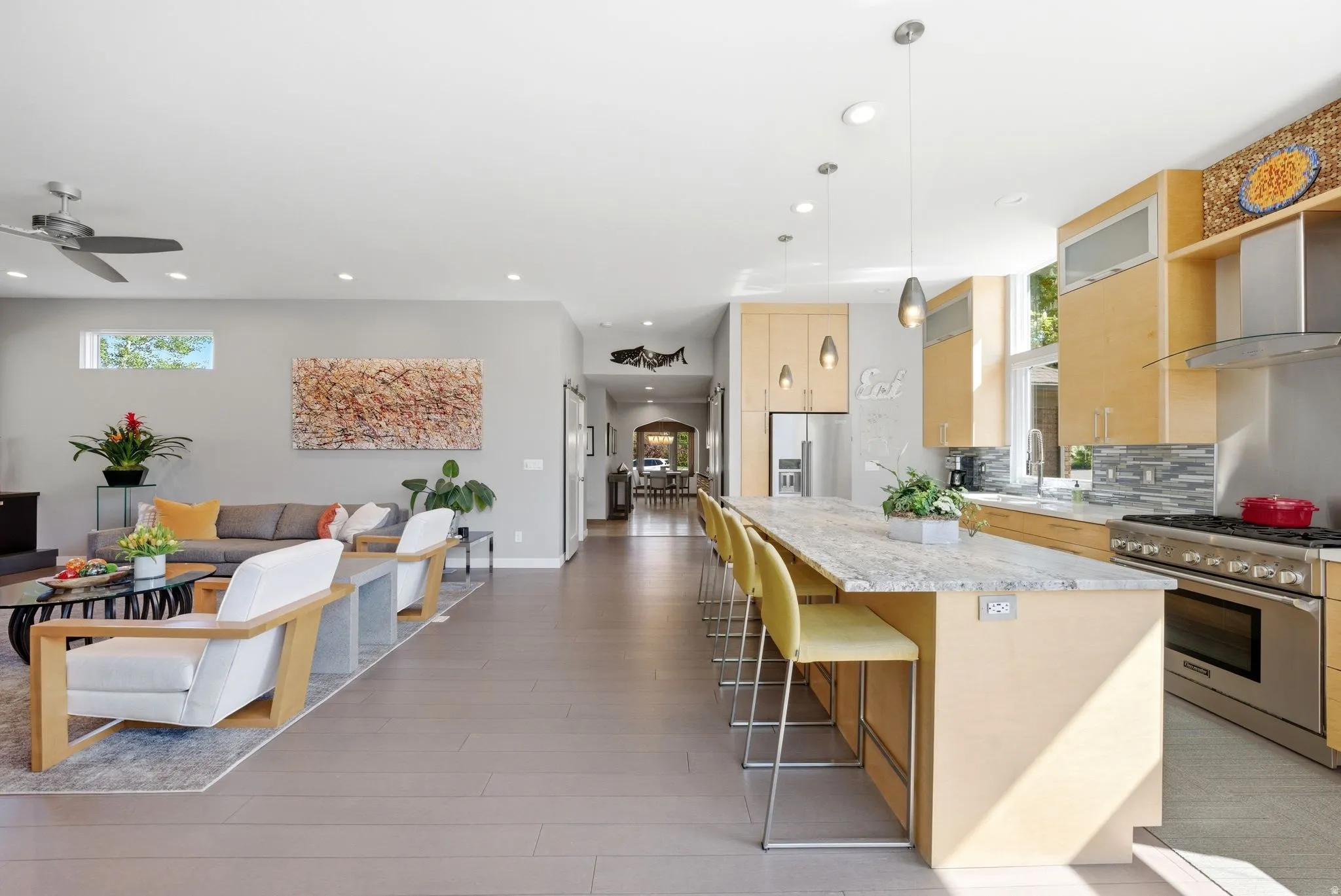 Modern kitchen featuring light wood cabinetry, a large center island with a light-toned countertop, and stainless steel appliances
