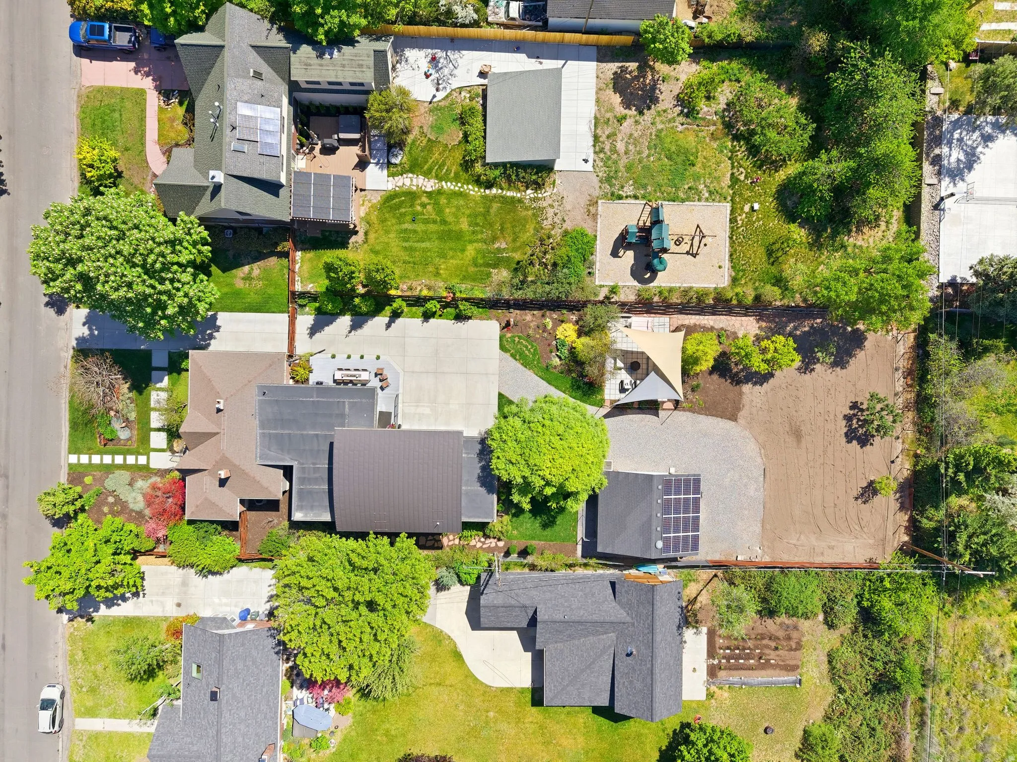 Expansive property featuring multiple structures, mature trees, and a large paved driveway