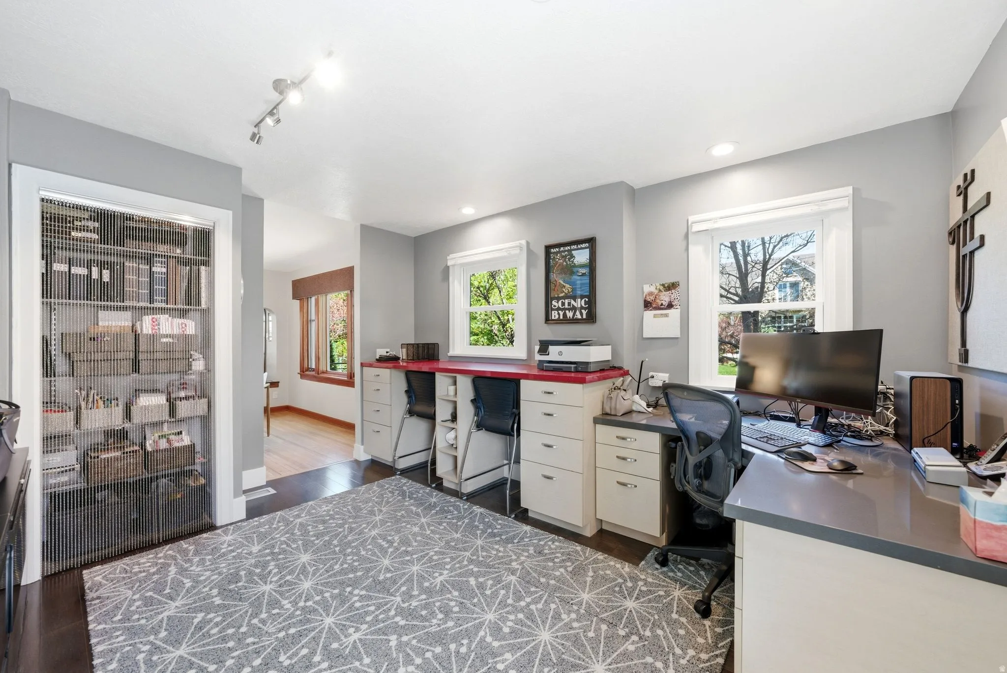 Dedicated workspace featuring multiple built-in desks, recessed lighting, and a large window