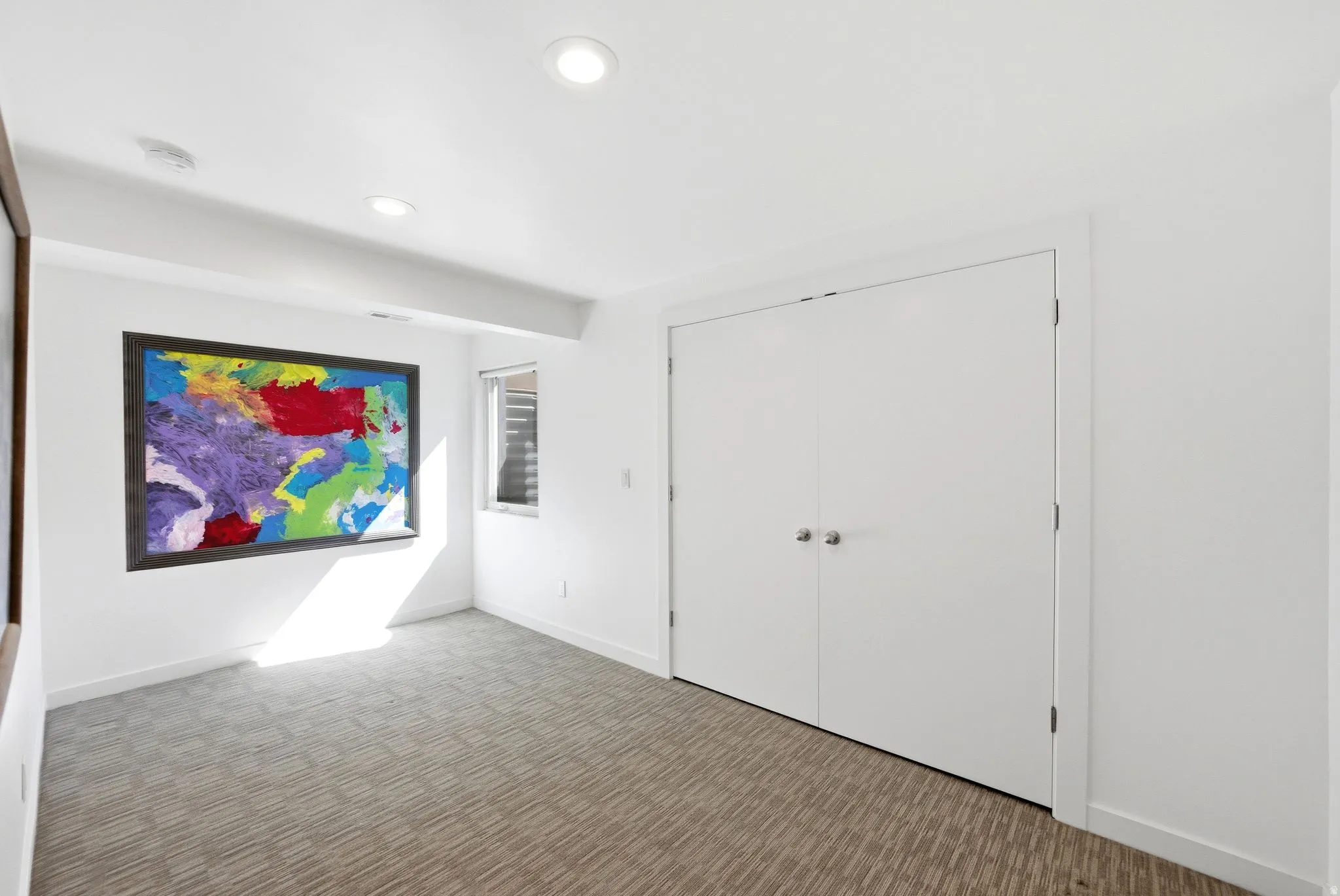 Room featuring neutral patterned carpet, recessed lighting, and a window with horizontal blinds