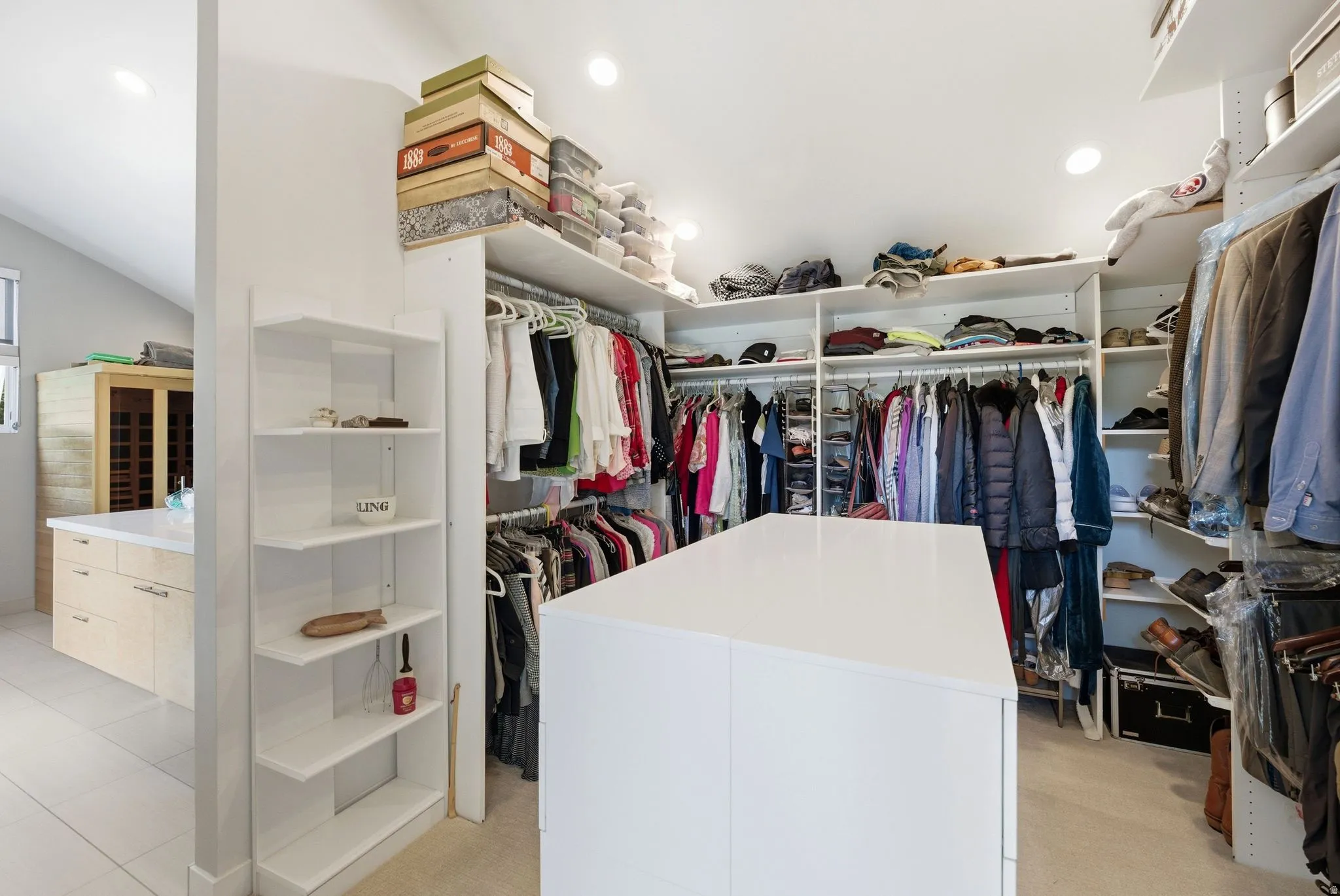Custom closet system featuring a central island, extensive hanging rods, multiple shelving units, and recessed lighting