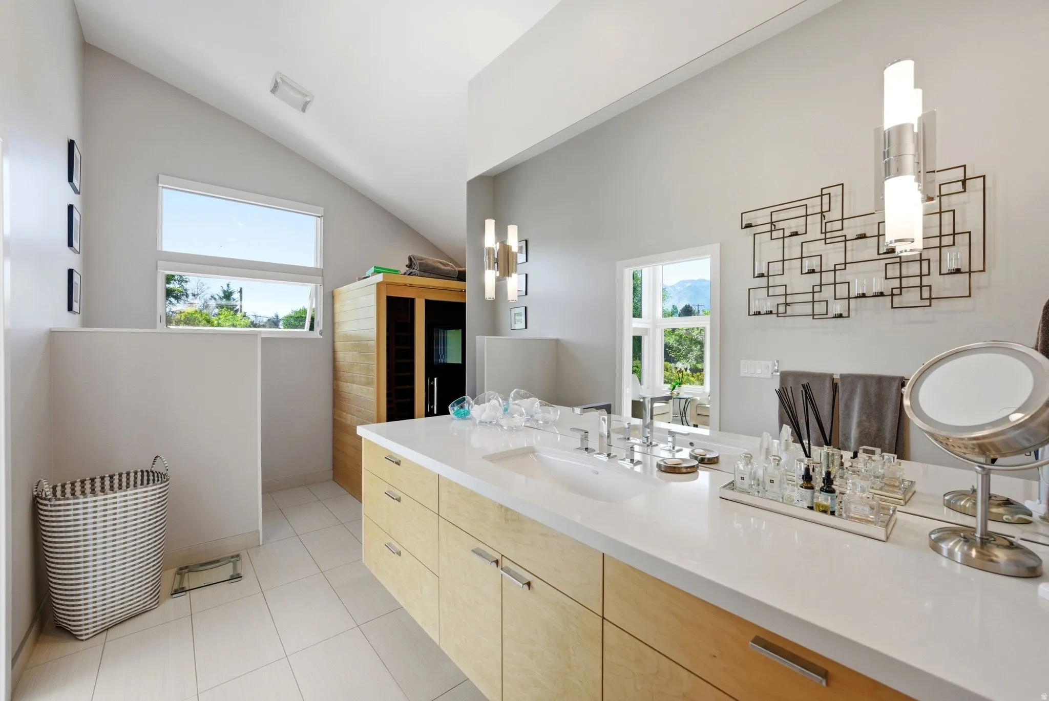 Contemporary bathroom featuring a light wood-finish vanity with dual sinks, white countertop, and tiled flooring