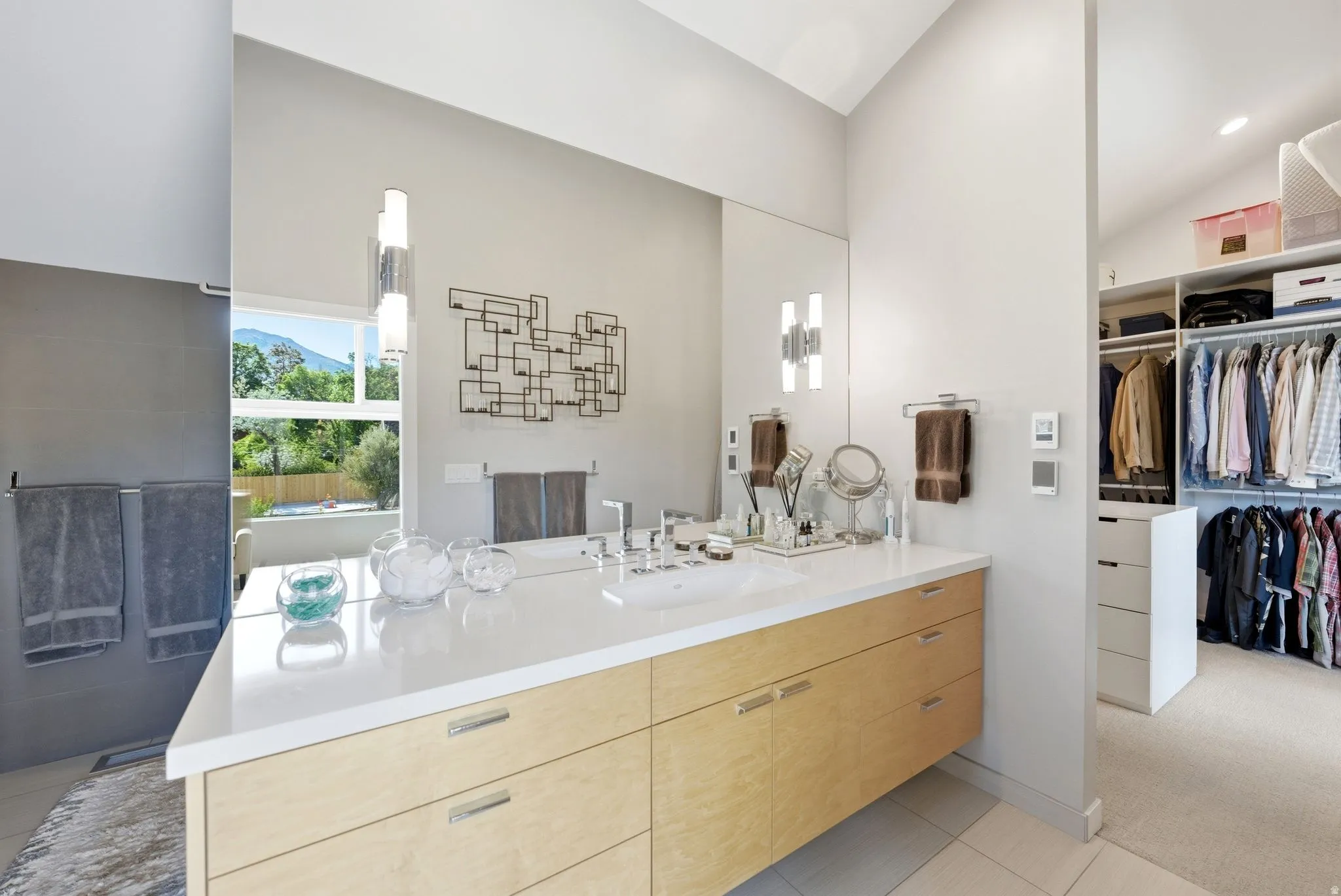 Spacious bathroom featuring a double vanity with light wood-finish cabinetry and a white countertop