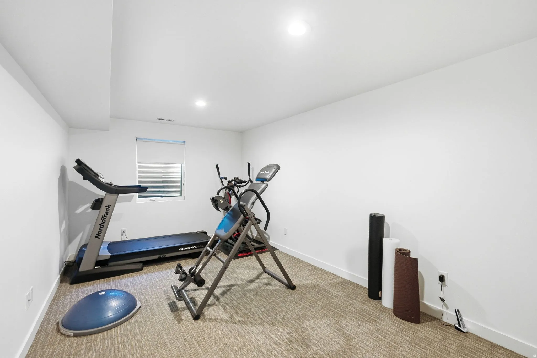 Spacious room featuring neutral carpeting, recessed lighting, and a single window with blinds