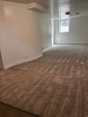 Room featuring a neutral wall color, built-in ceiling lighting, a window, baseboard trim, and a patterned carpet