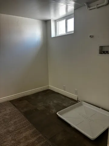 Room featuring a window, painted walls, baseboards, and mixed flooring with carpet and wood-finish sections