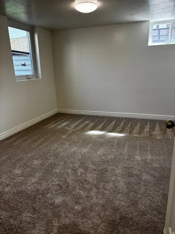 Neutral wall paint with textured carpet flooring, white baseboards, and two windows