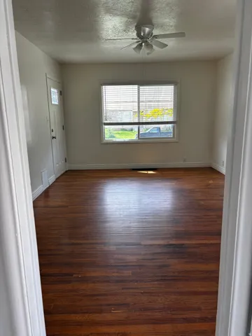 Wood-finish flooring throughout, featuring a white ceiling fan with integrated lighting
