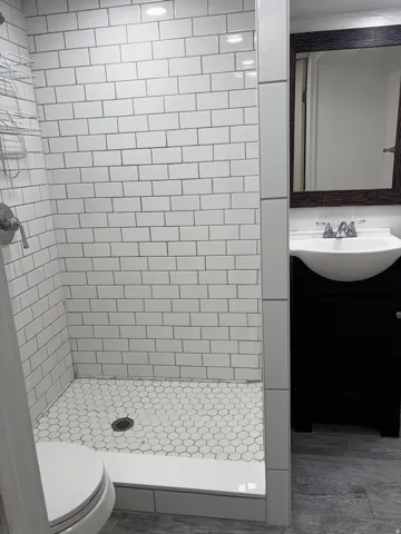 Bathroom featuring a shower with white subway tile walls and a hexagonal tile floor