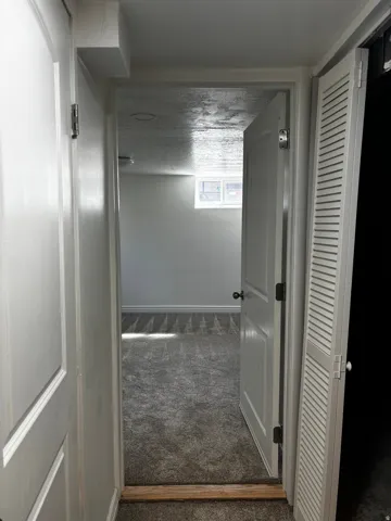 Interior space featuring gray carpet flooring, white painted walls, and a window providing natural light