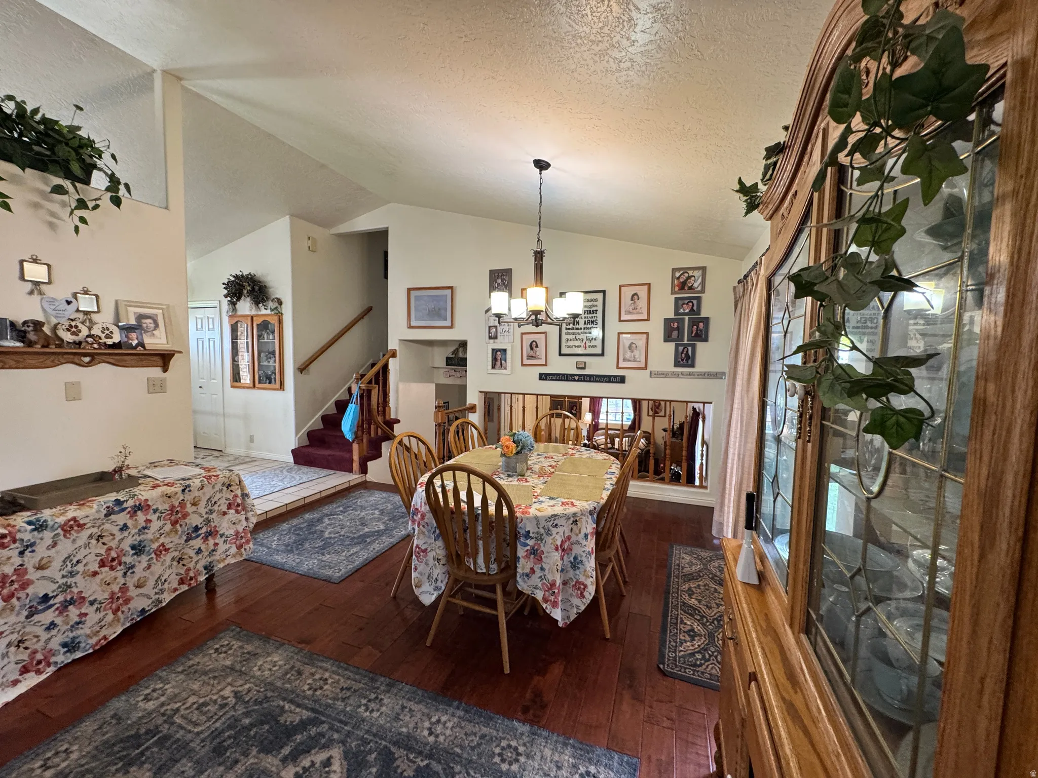 Open-concept dining area featuring wood-finish flooring, a vaulted ceiling, and an architectural half-wall