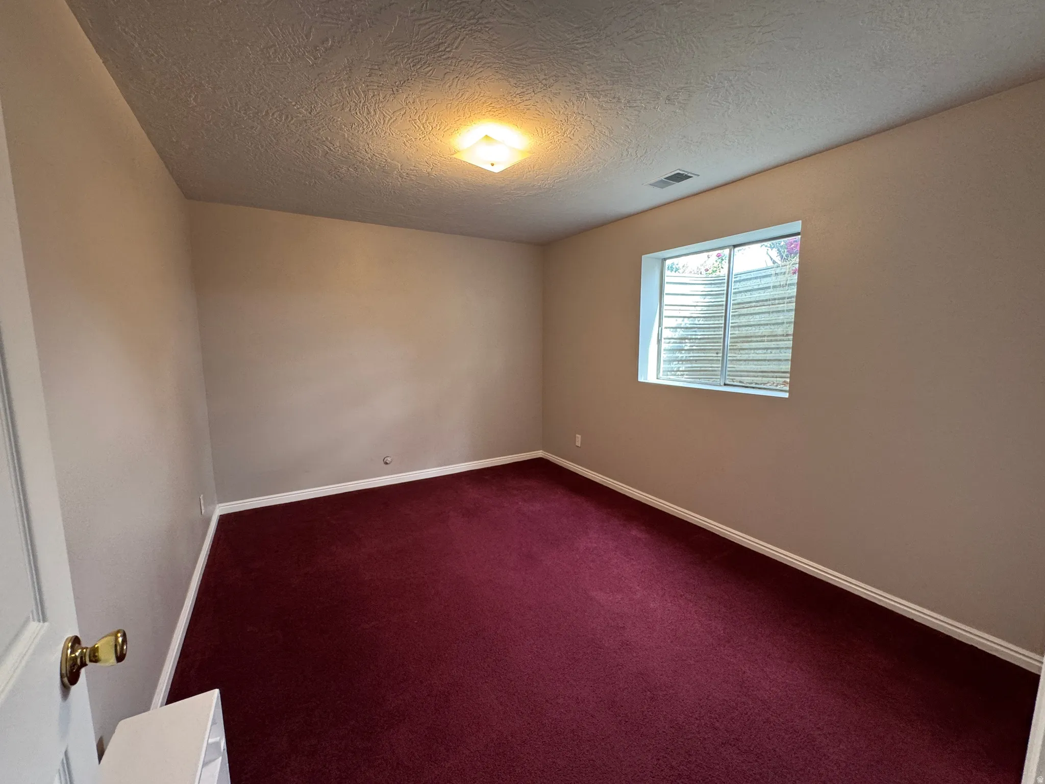 Spacious room featuring neutral painted walls and deep red carpeting