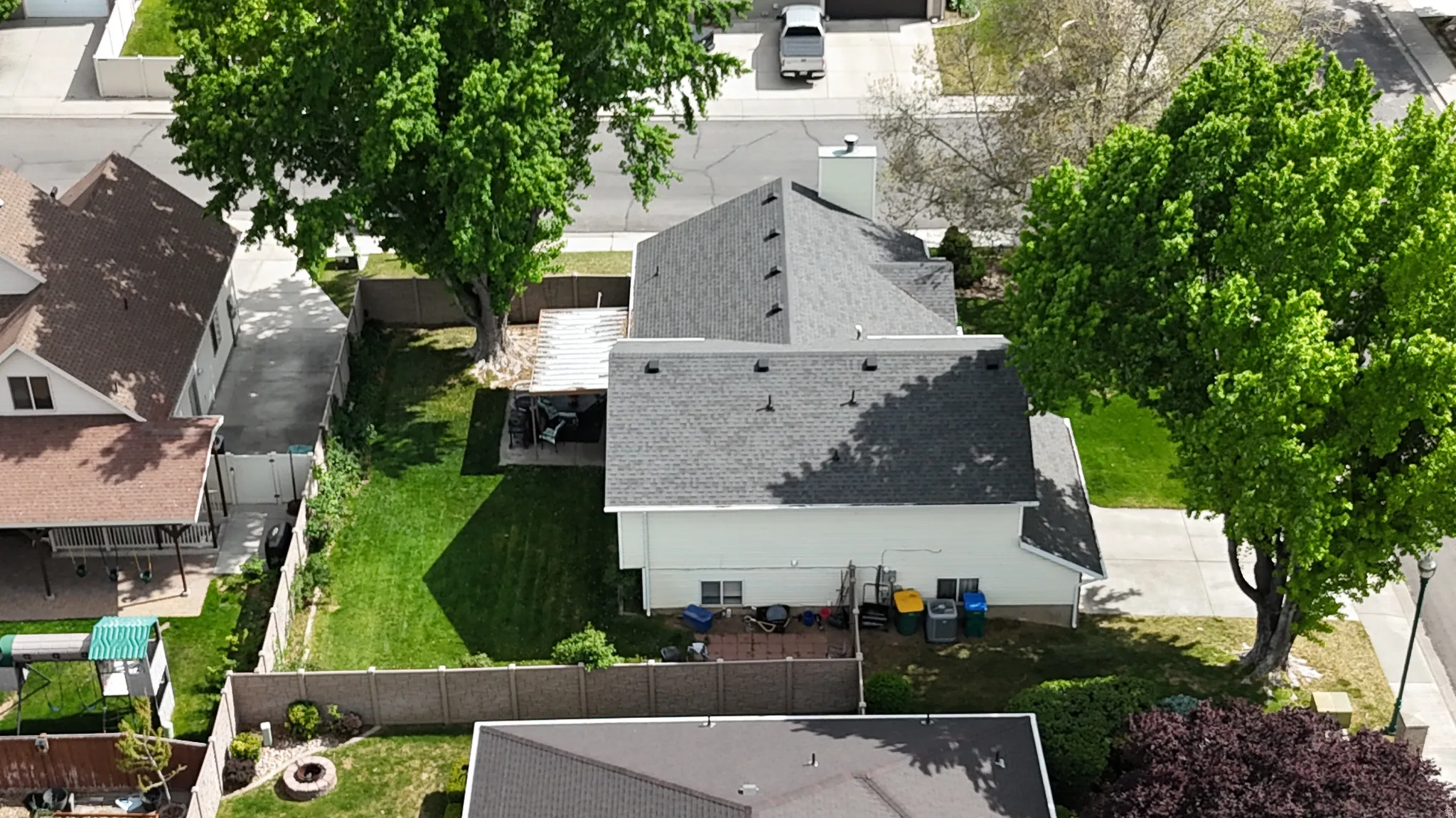 Expansive backyard with a manicured lawn, established trees, and perimeter fencing