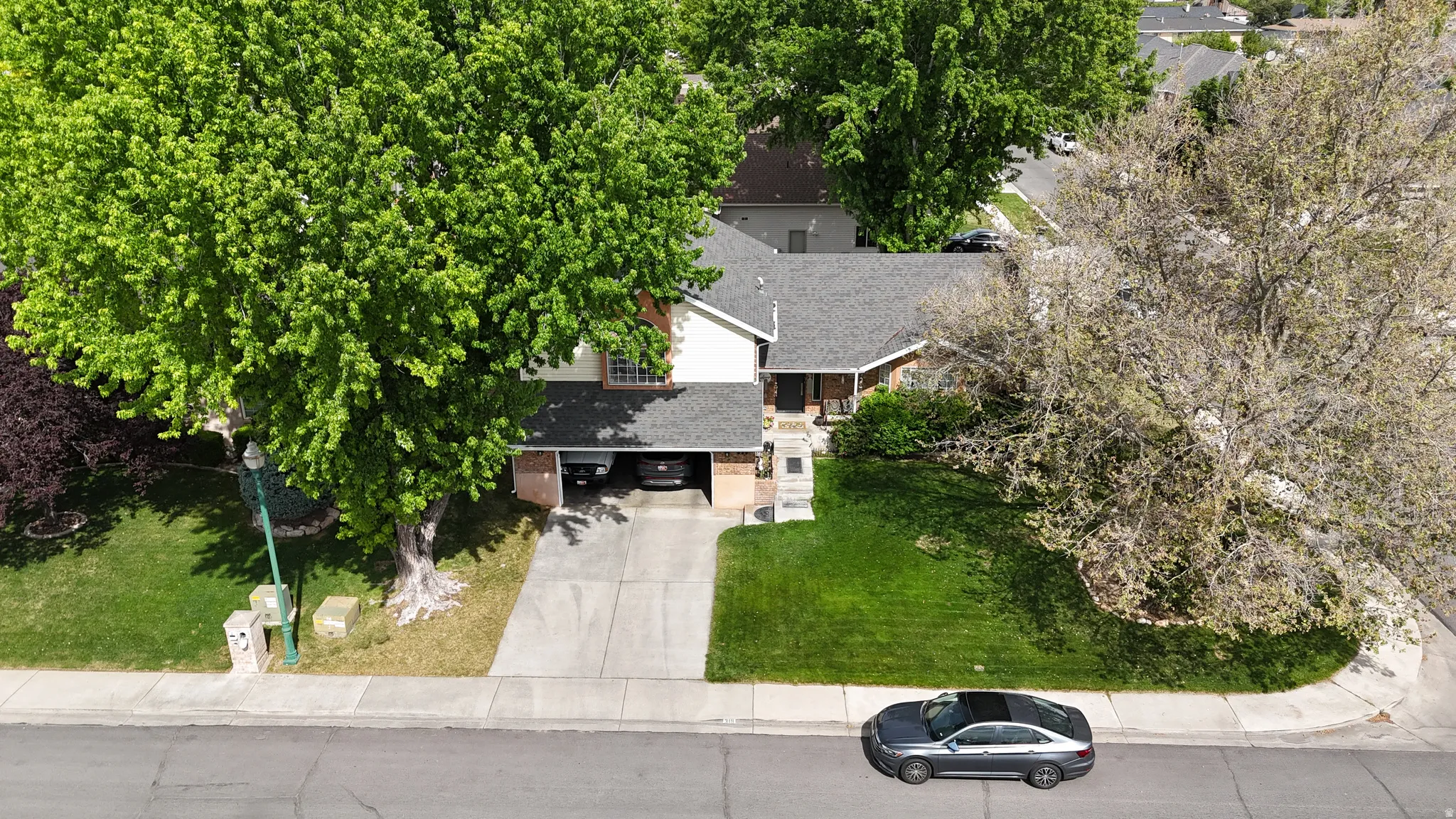 Two-story residence featuring a gray shingle roof and a concrete driveway