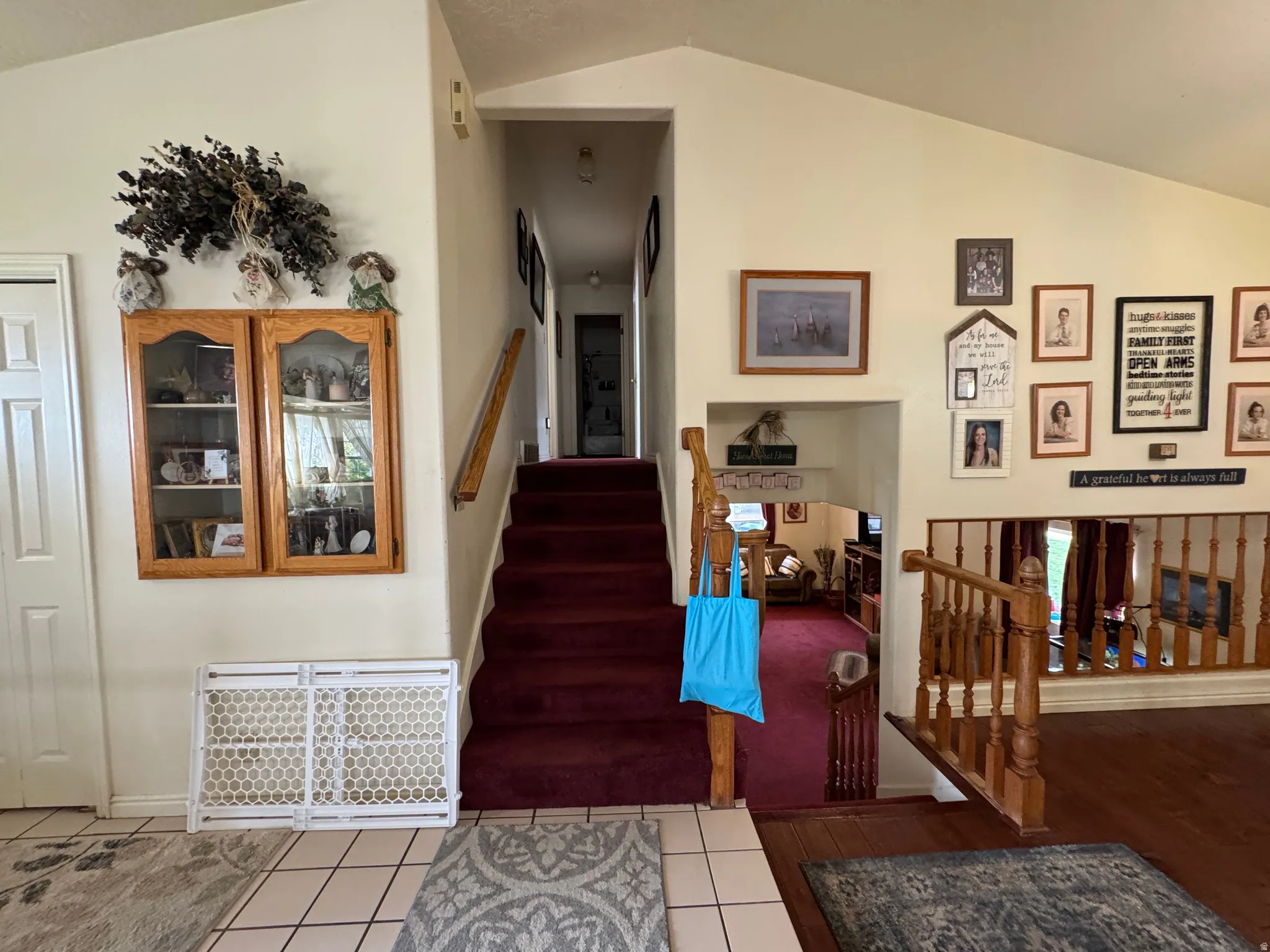 Interior featuring a vaulted ceiling and a staircase with a red carpet runner