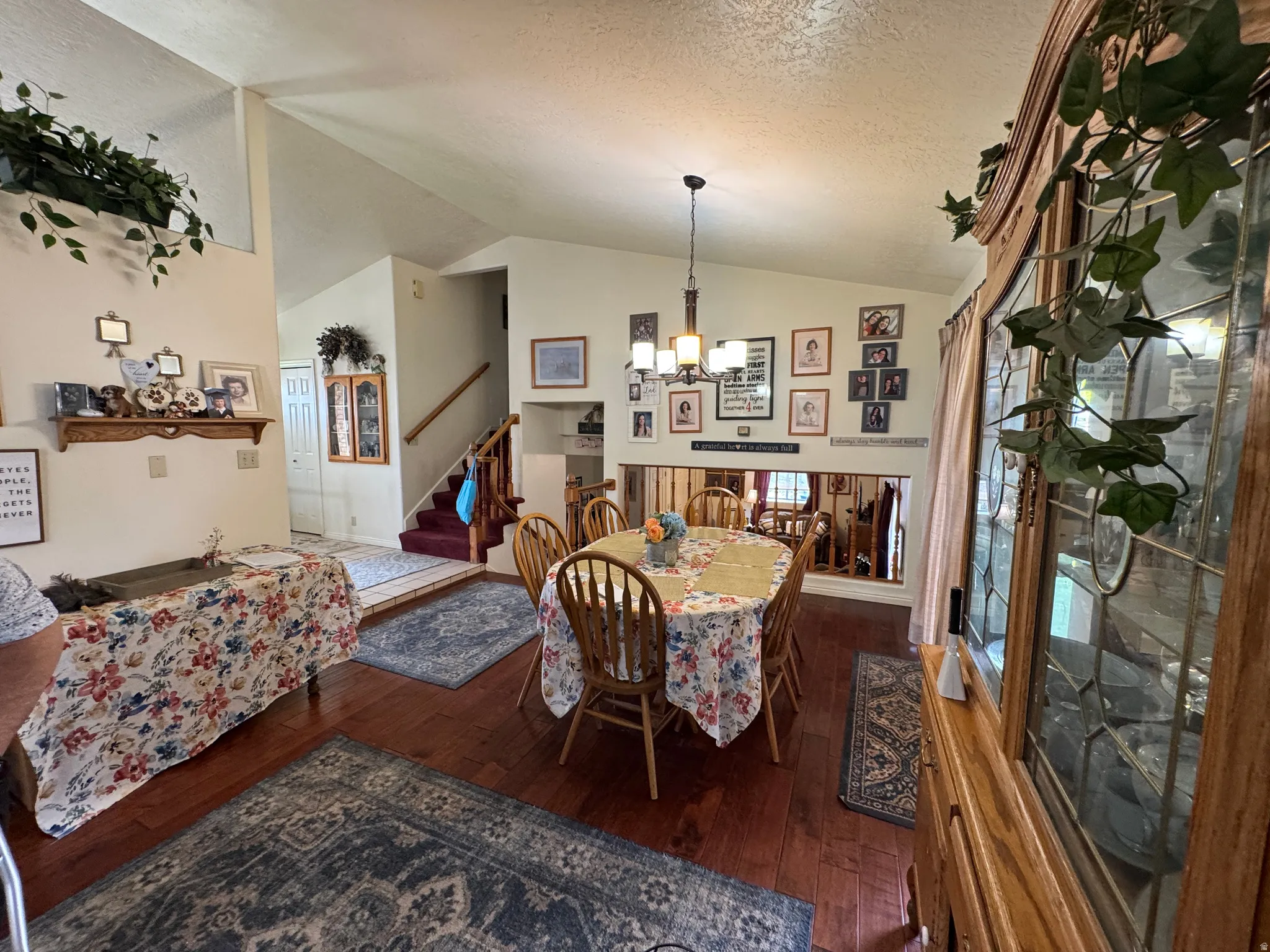 Dining area featuring wood-finish flooring, a contemporary chandelier, and vaulted ceilings