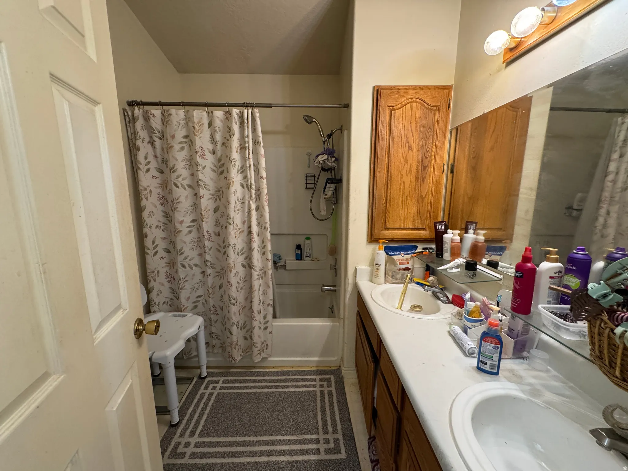 Bathroom featuring a double vanity with integrated sinks, wood-finish cabinetry, and a full-width mirror