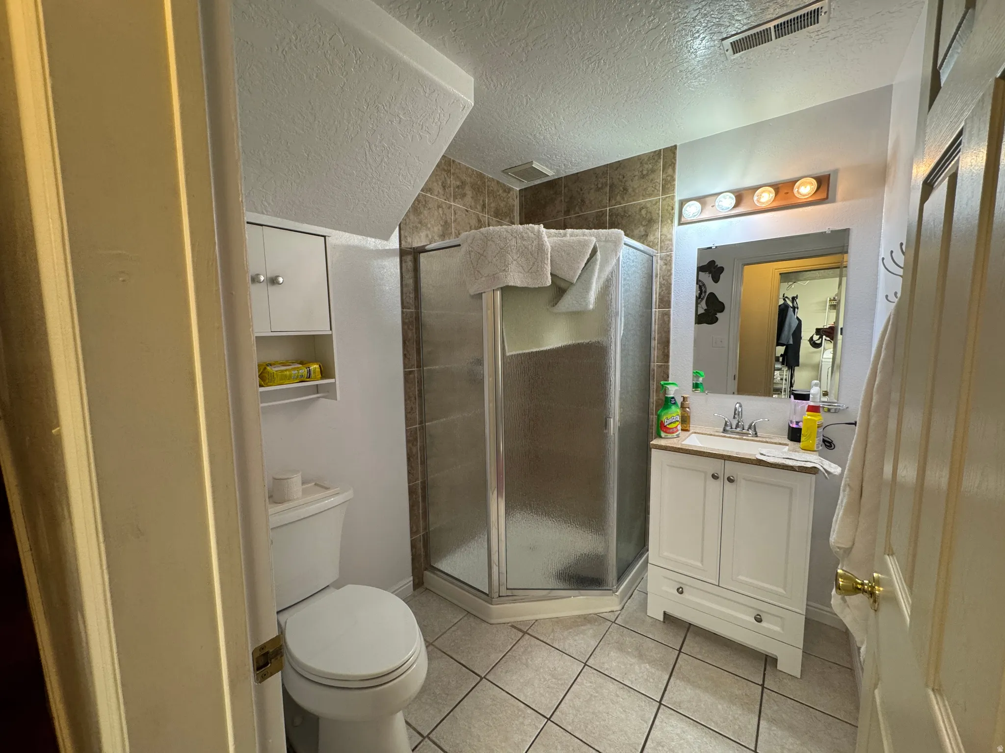Bathroom featuring a corner shower enclosure, white vanity with a wood-finish countertop, and a wall-mounted light fixture