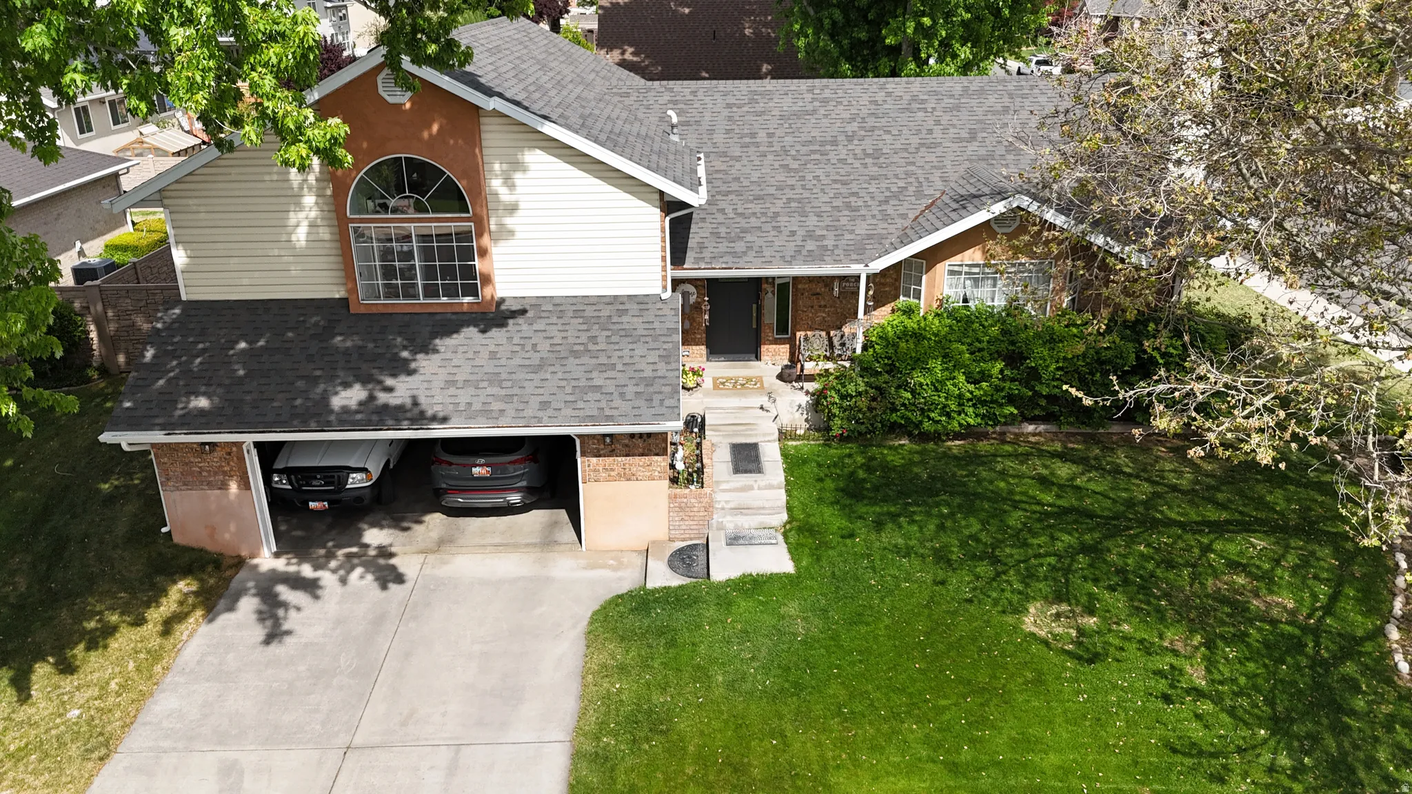 Multi-level residence featuring a prominent arched window, brick detailing, and siding accents