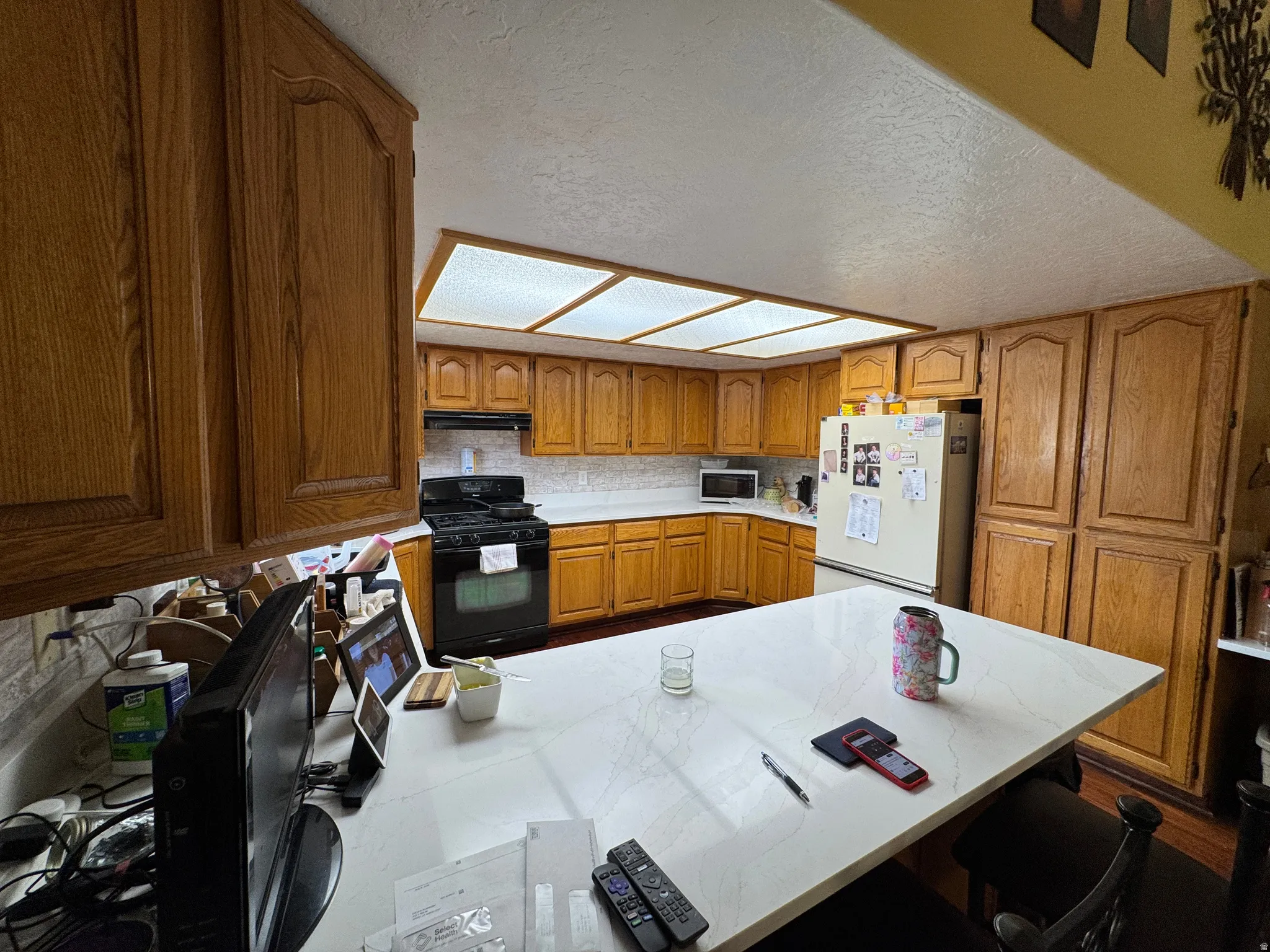 Kitchen featuring extensive wood cabinetry, a central island with a white countertop, and a built-in cooktop with an overhead microwave