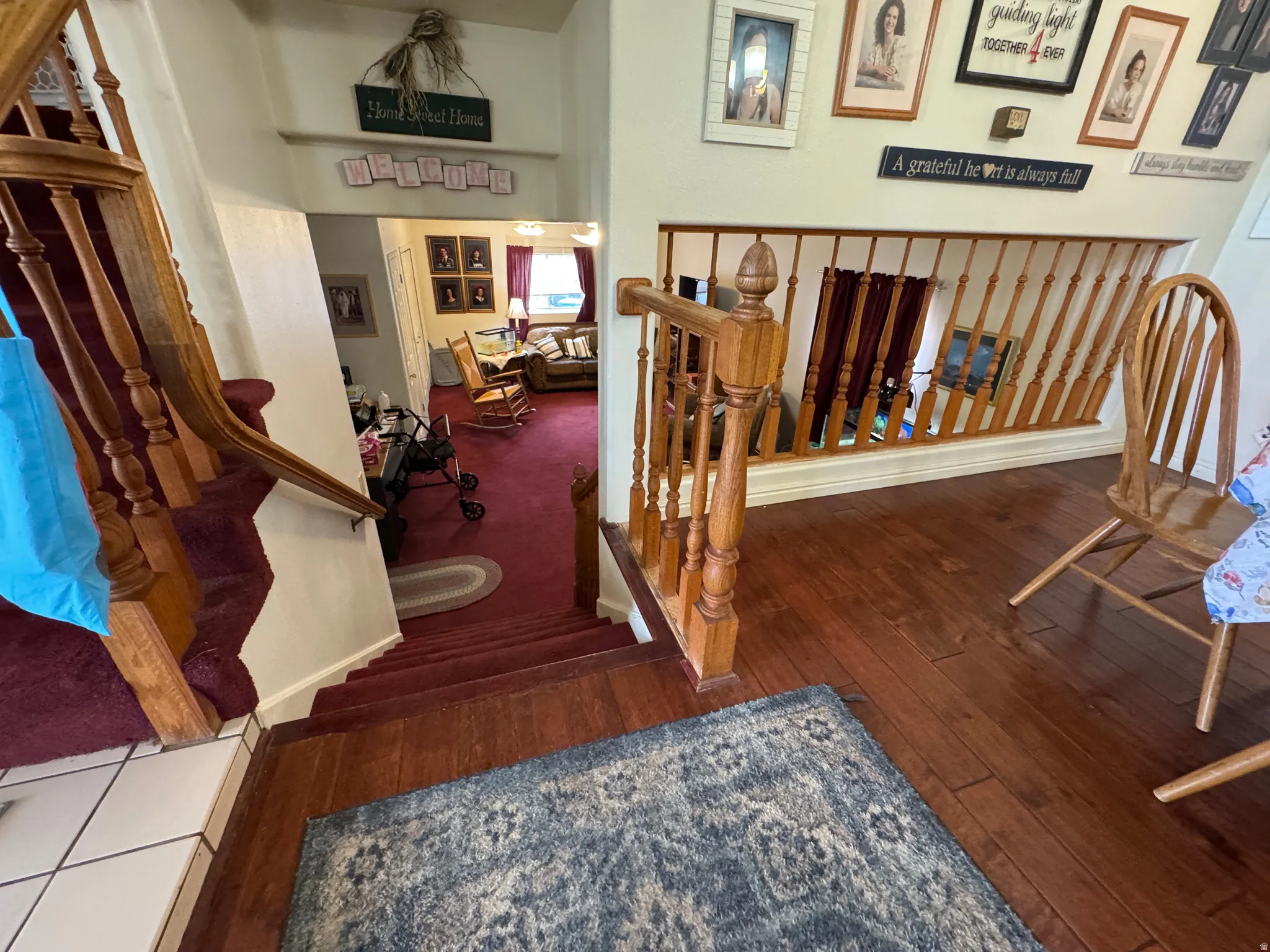 Wood-finish flooring and carpeted stairs featuring wood balusters and handrails