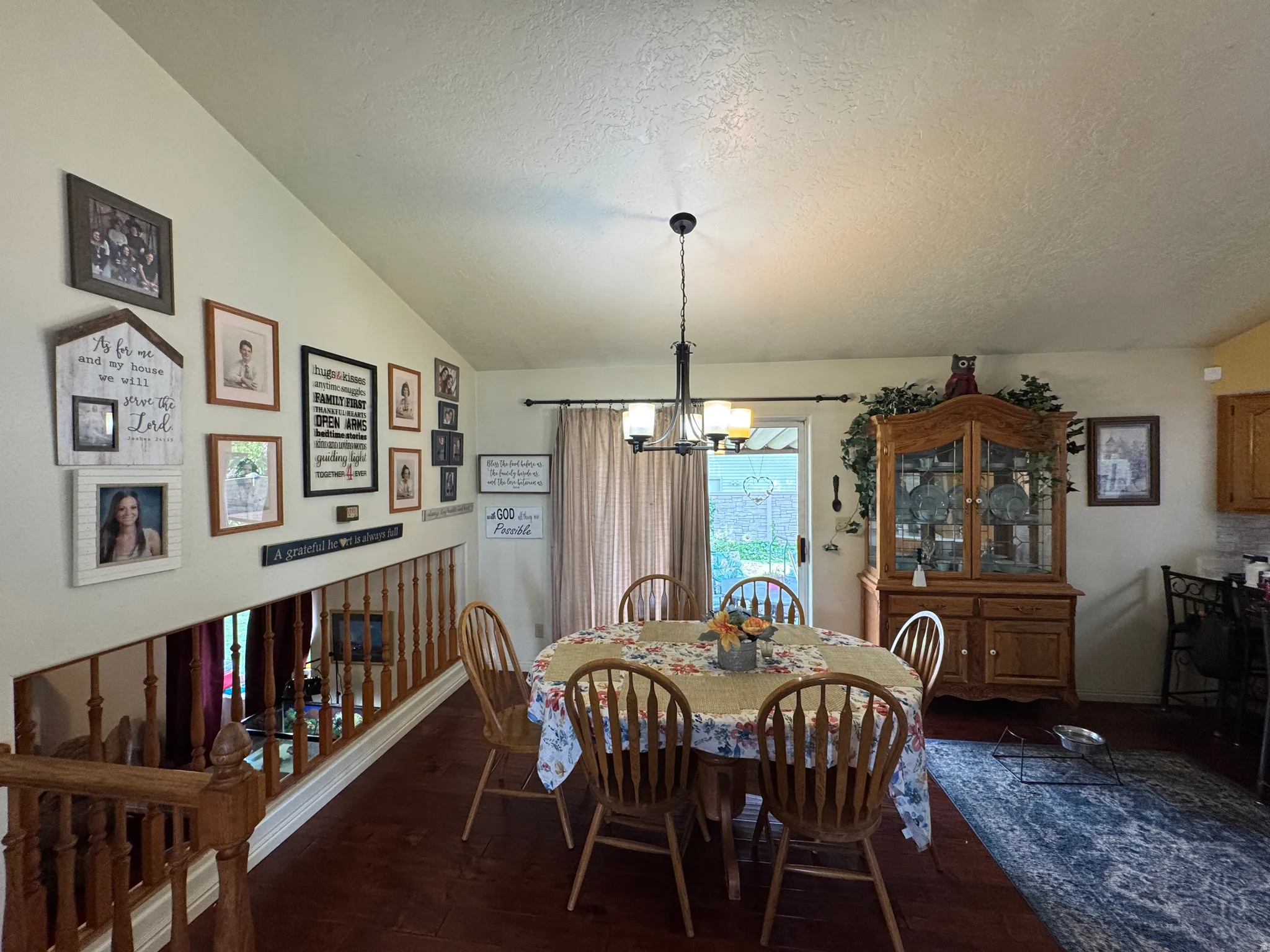 Dining area featuring wood-finish flooring, a vaulted ceiling, and a contemporary chandelier