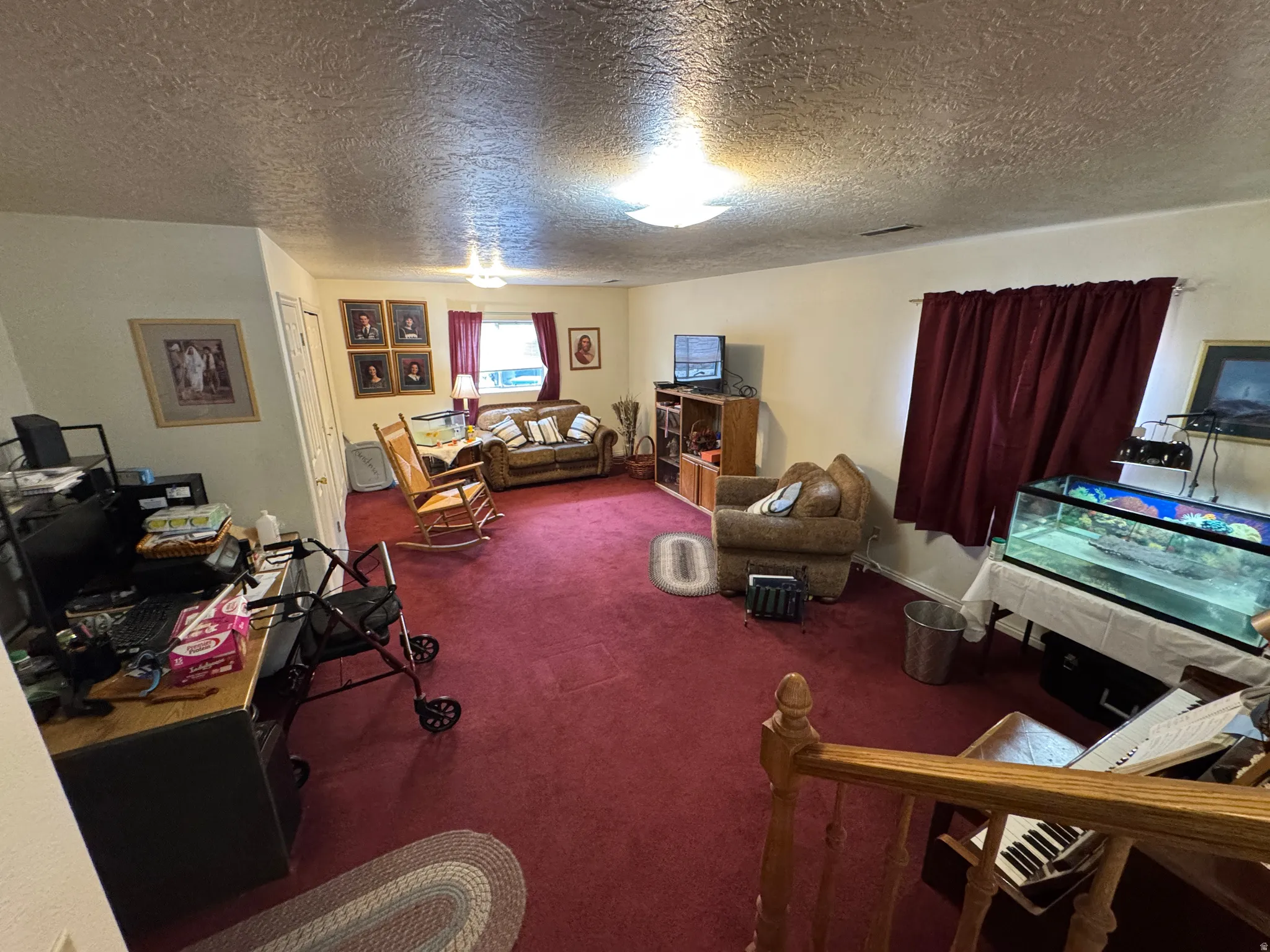 Spacious interior with textured ceilings, two windows, and red carpeting