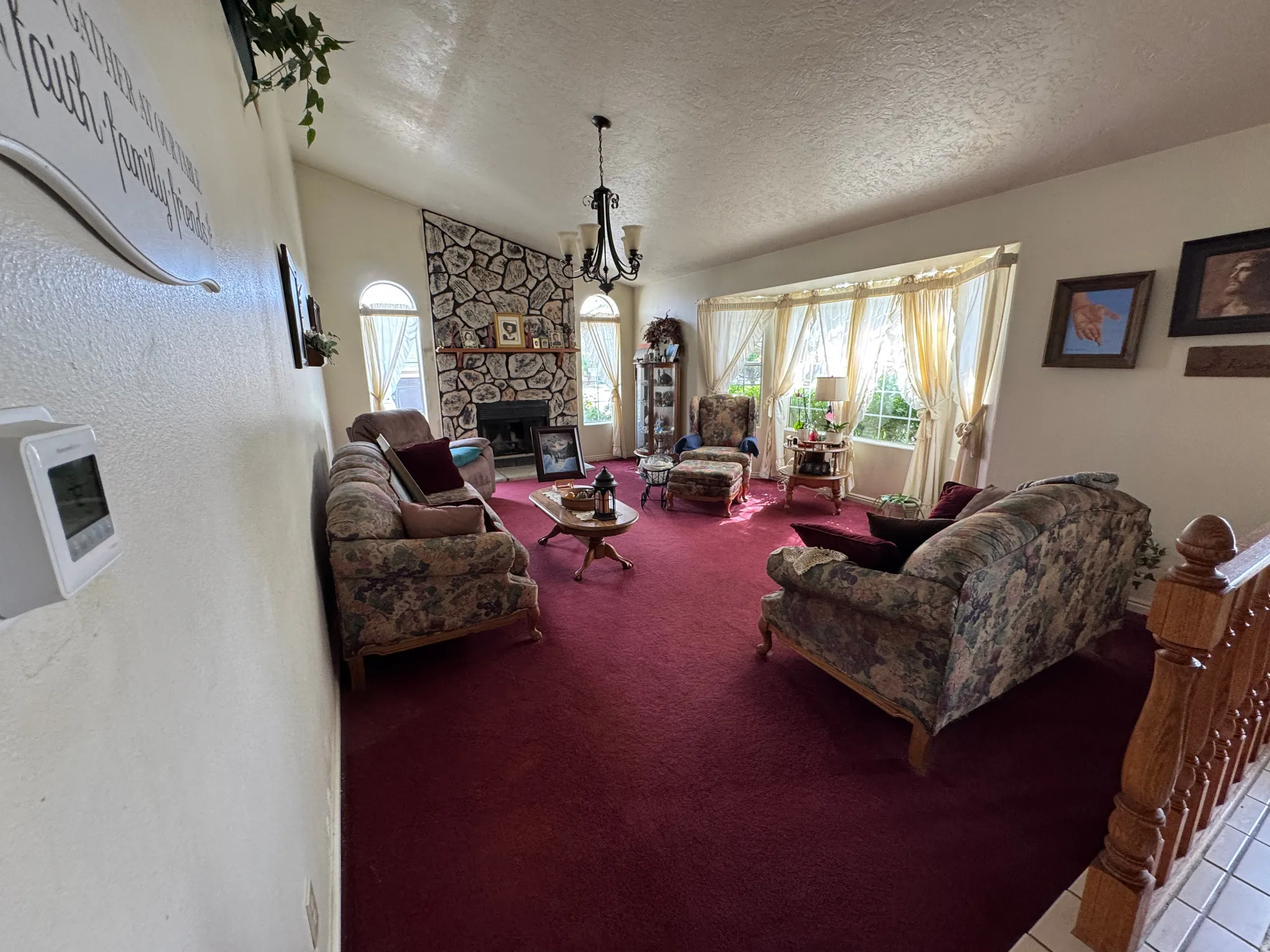 Living area featuring a stone-clad fireplace, vaulted ceiling, and a prominent bay window