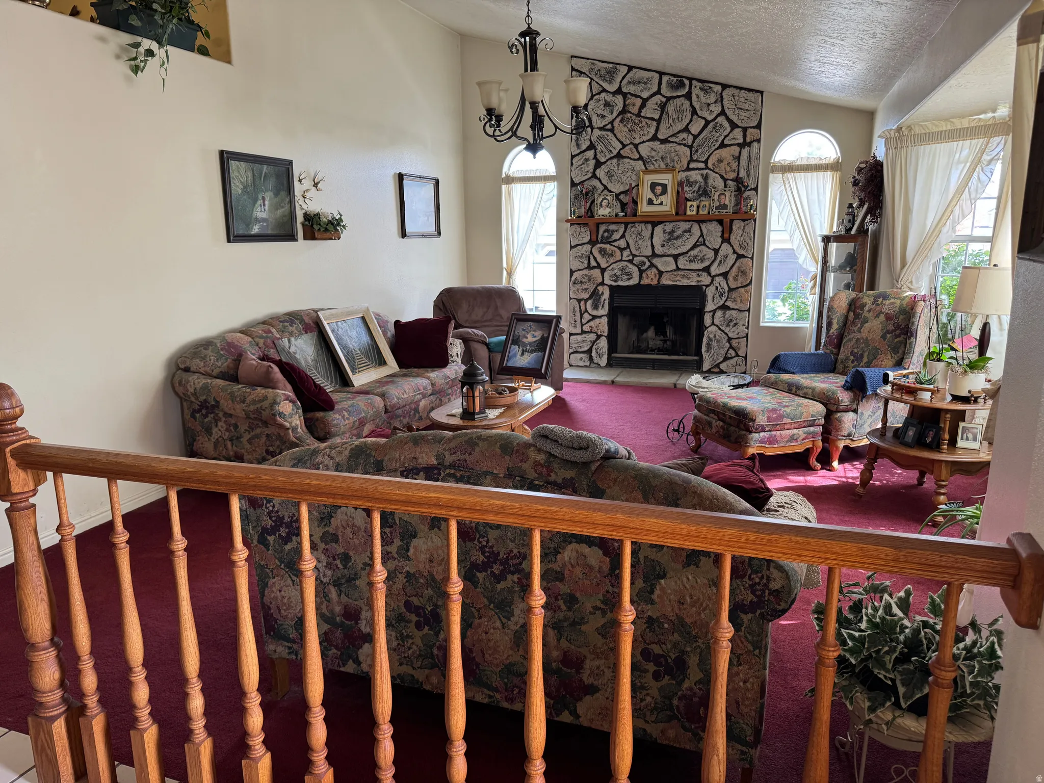 Spacious living area featuring a vaulted ceiling and a stone-clad fireplace