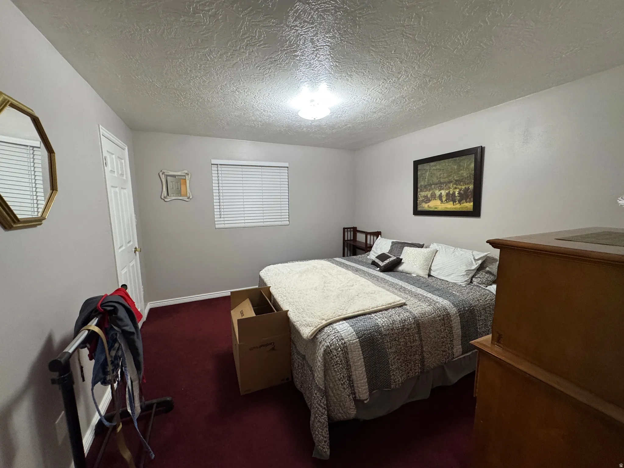 Interior room featuring light gray walls, a textured white ceiling, and rich red carpeting