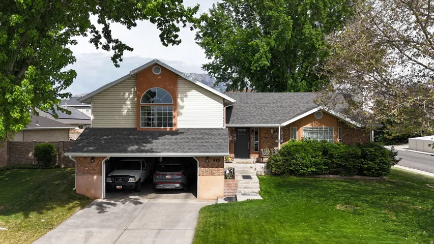 Split-level residence featuring a two-car garage, brick and siding exterior, and a prominent arched window on the upper level