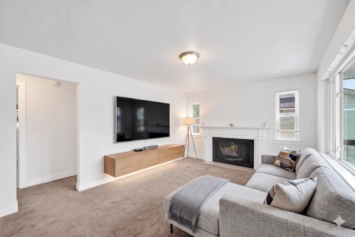 Living area featuring a fireplace with a white mantel, recessed firebox, and large windows