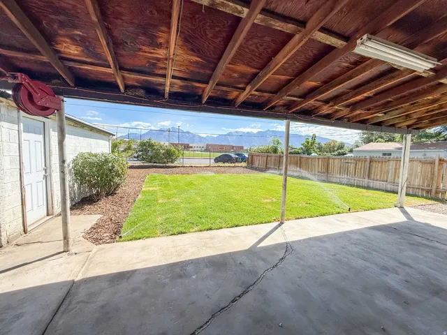 Covered patio area with a concrete surface, leading to a lawn with a sprinkler system