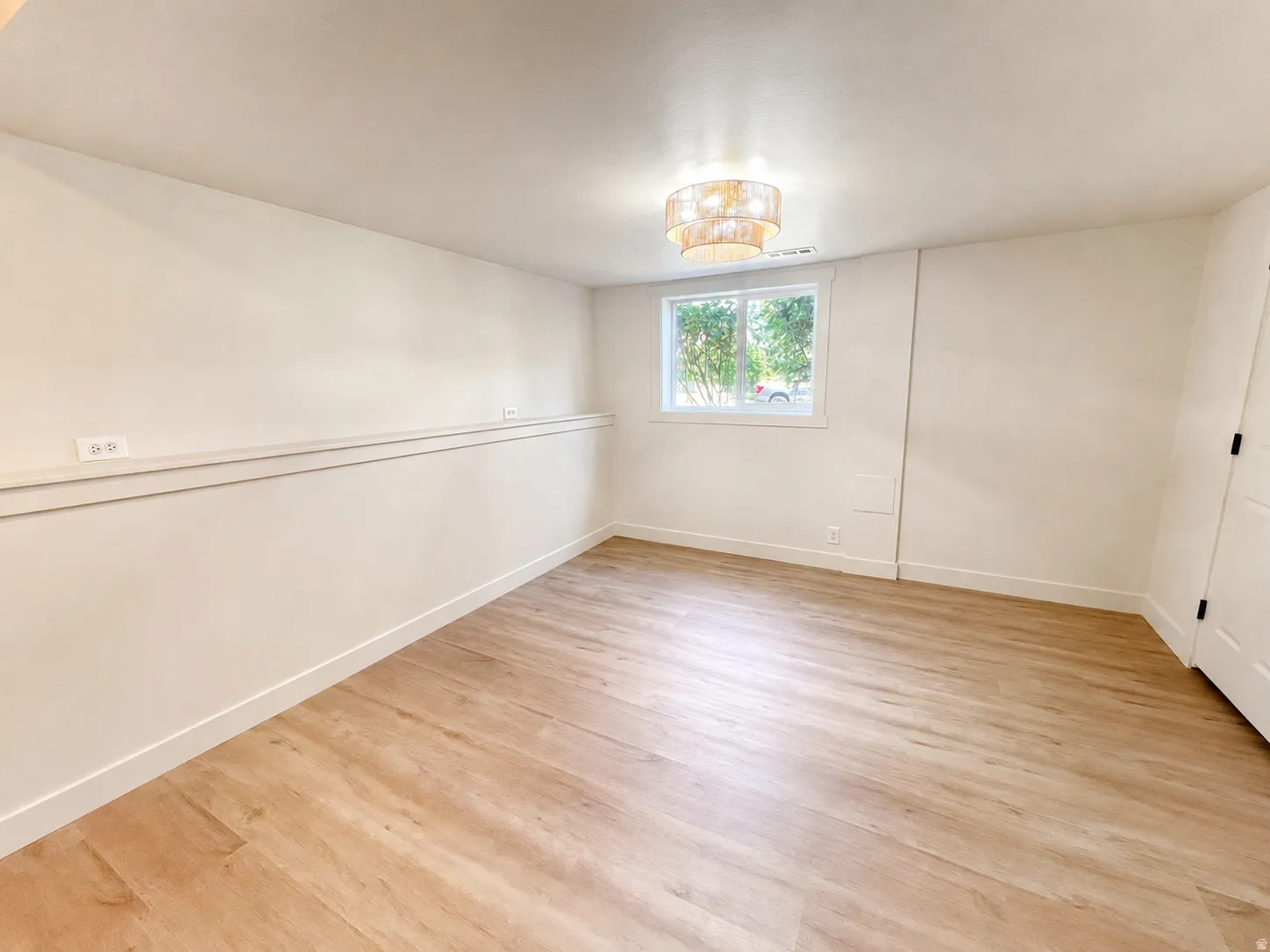 Bedroom 4 in basement--bright interior space featuring light wood-finish flooring