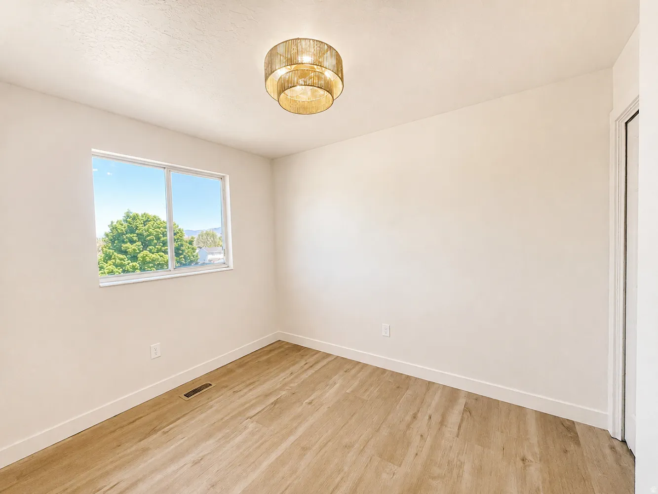 Bedroom 2 upstairs with neutral wall finishes, wood-finish flooring, and a modern drum chandelier create a versatile interior space
