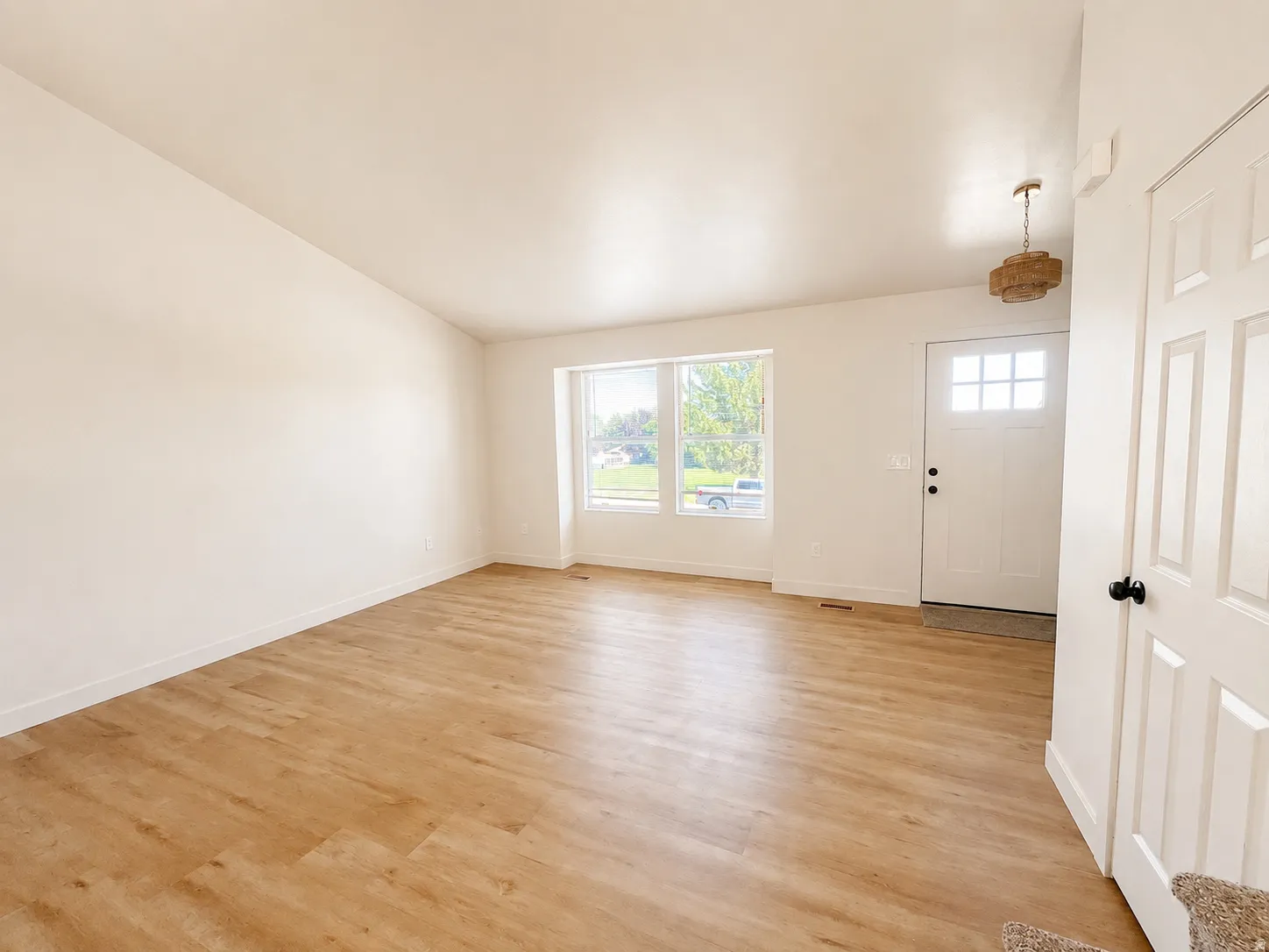Open-concept living space with wood-finish flooring, white trim, and neutral wall tones