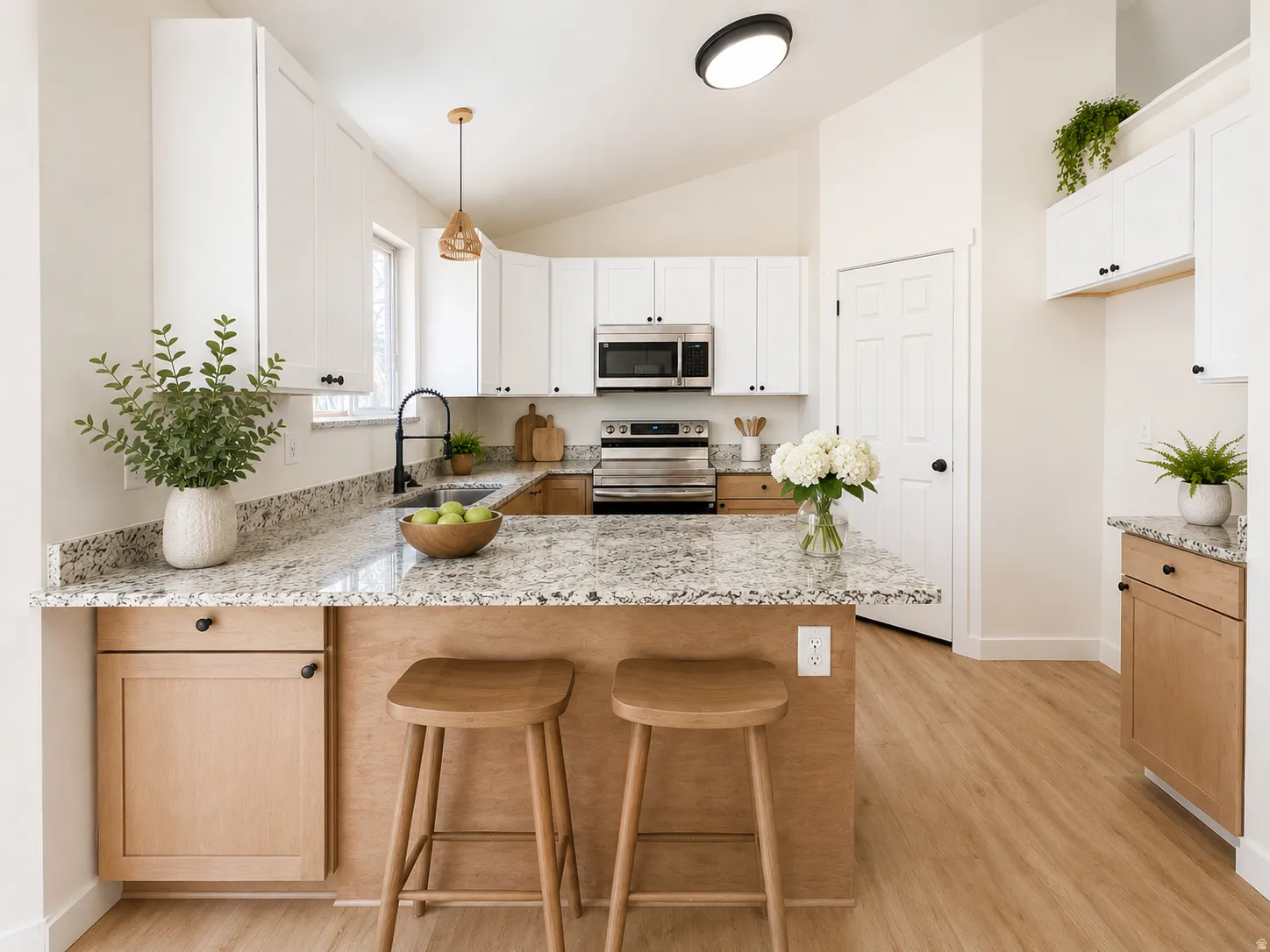 Kitchen featuring granite countertops, wood-finish flooring, white upper cabinetry, and light wood-tone lower cabinetry--virtually staged.