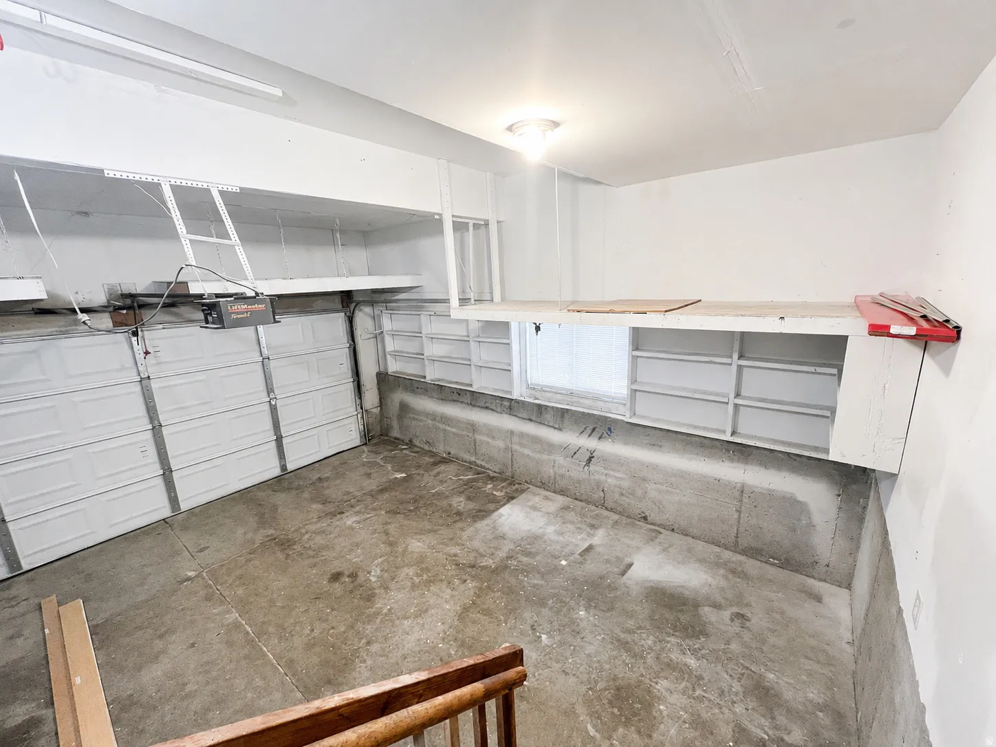 Attached 2-car garage featuring a concrete floor, built-in shelving, and an overhead storage platform