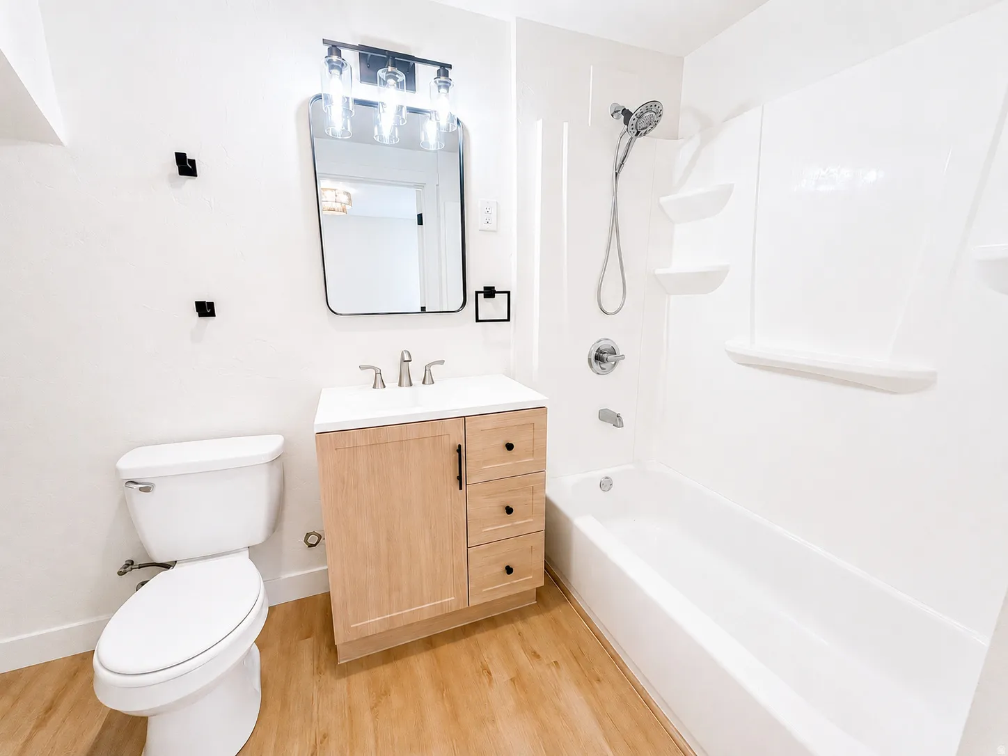 Full bathroom in basement featuring a light wood-finish vanity with a white countertop and rectangular sink