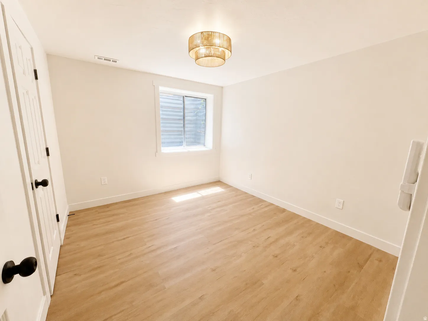 Bright office featuring wood-finish flooring, white baseboards, and a contemporary ceiling fixture