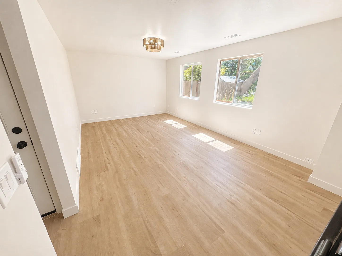 Bright interior space featuring light wood-finish flooring, white walls, and white baseboards
